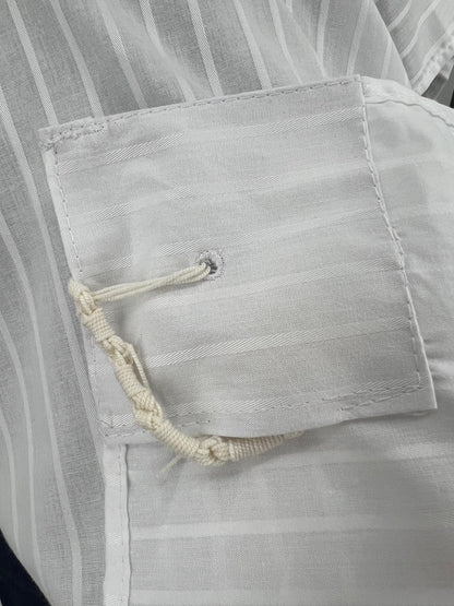 Close-up of a white poly-cotton Tallit Katan corner, showing reinforced stitching and a tzitzit string