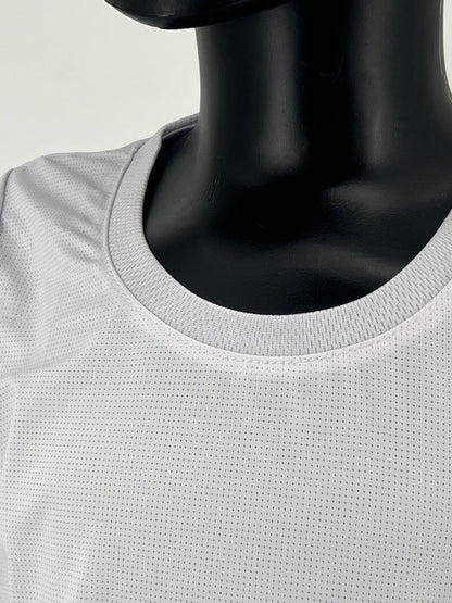 Close-up view of a mannequin wearing a white round-neck Tzitzit T-shirt made from breathable, mesh fabric. The image focuses on the neckline and upper chest area, highlighting the texture and stitching of the garment. Background is plain and light-colored.