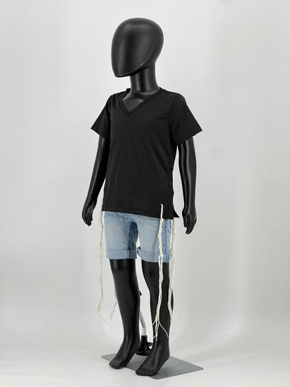 Full-body view of a mannequin wearing a black V-neck short-sleeve Tzitzit T-shirt paired with light blue denim shorts. Four white Tzitzit fringes hang from the garment’s corners, in line with traditional Jewish practice. The mannequin stands on a gray display base against a plain light background.