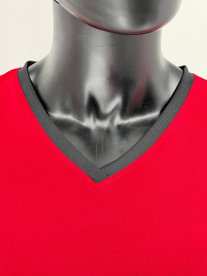 Close-up of a red athletic Tzitzit T-shirt neckline on a black mannequin, featuring a contrasting black V-neck collar with textured stitching.