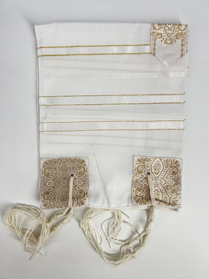 Folded white children's tallit (Jewish prayer shawl) featuring gold stripes, decorative gold corner reinforcements