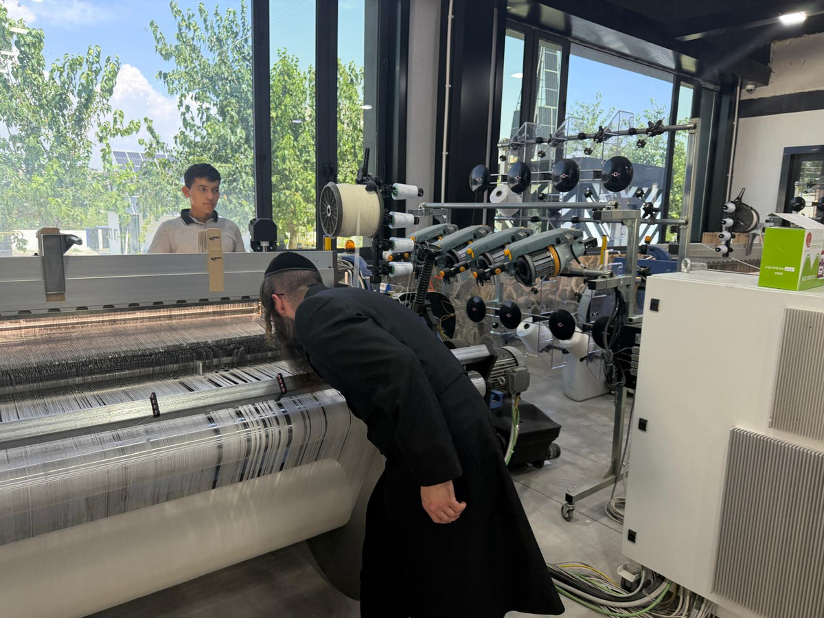 Examination of a tallit weaving loom during the Edah HaChareidis visit to the Melechet Machshevet factory