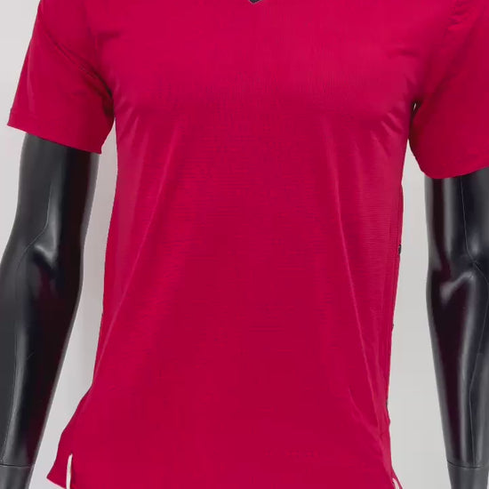Video of a red athletic Tzitzit T-shirt with a black V-neck, worn by a black mannequin. The shirt features side snap closures and traditional white Tzitzit strings hanging from the hem, combining halachic requirements with a modern sporty design.